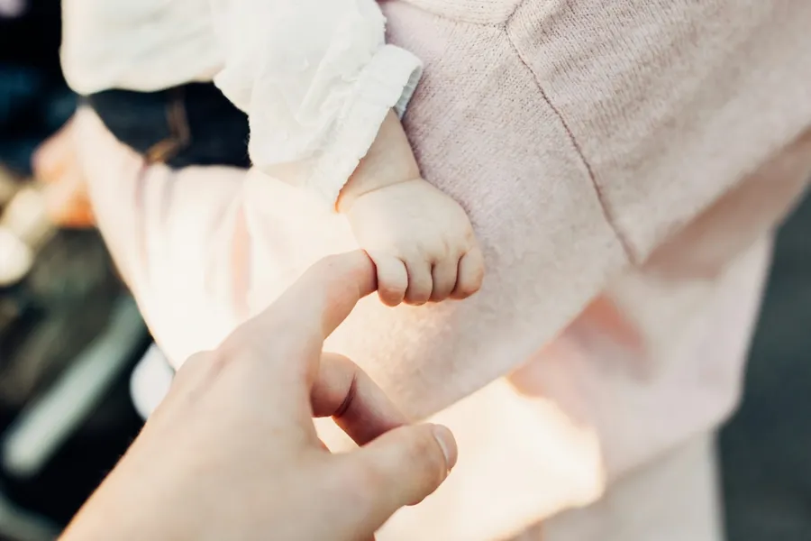 une petite main de bébé tenant le doigt d'un adulte