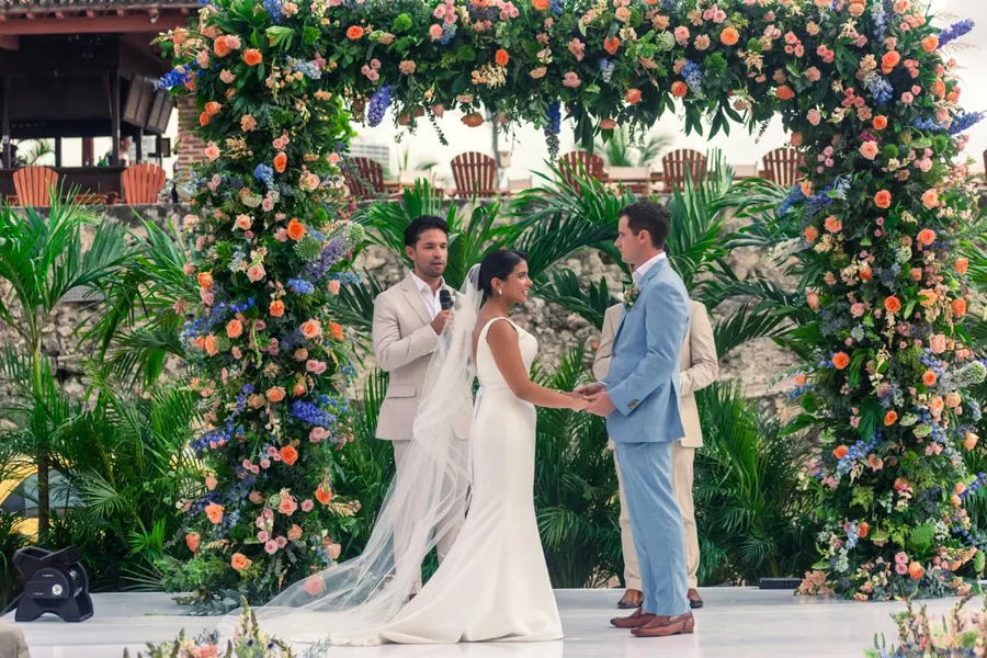 mari et femme sous une arche de fleurs, prononçant leurs voeux de mariage