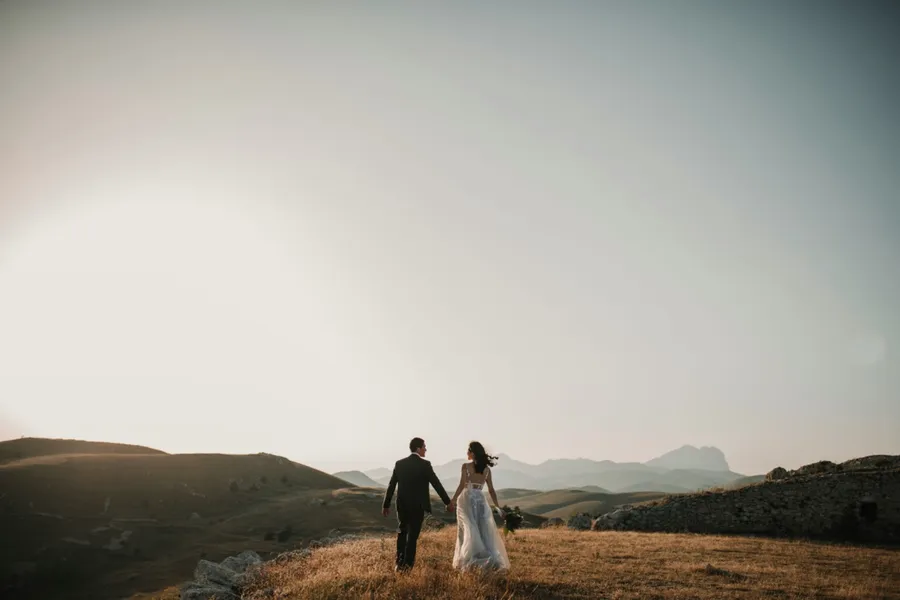 un couple de mariés dans une prairie qui se tient la main
