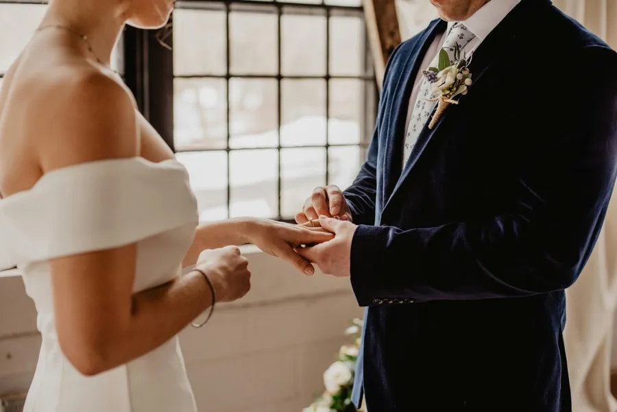 couple de mariés , l'homme met la bague au doigt de sa femme