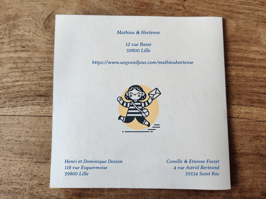 Faire part de mariage avec url personnalisée Un Grand Jour. Papier texturé sur une table en bois. Une fille heureuse tient une enveloppe dans ses mains sur un fond jaune orangé.