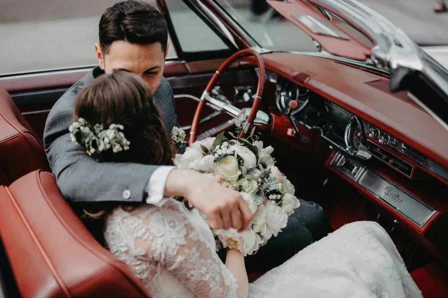 deux mariés amoureux dans une voiture vintage