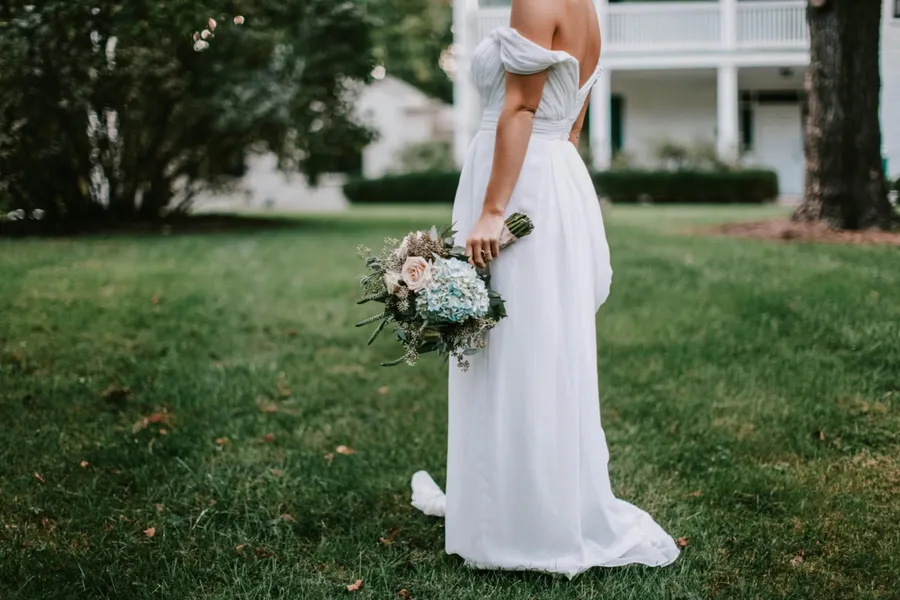 une femme qui tient son bouquet de mariée en robe blanche
